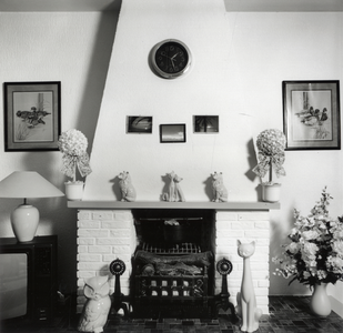 108266 Interieur van een huis aan de Orionstraat te Utrecht: woonkamer met open haard, schoorsteenmantel en diverse beeldjes.